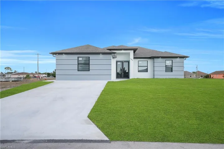 Prairie-style home with a front yard, driveway, and roof with shingles