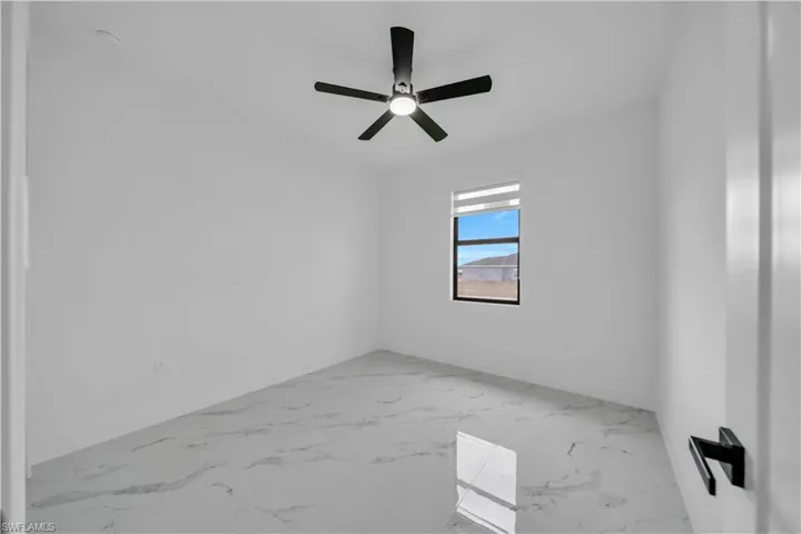 Spare room featuring light marble finish flooring and a ceiling fan