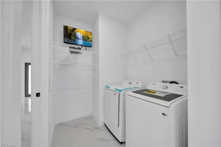 Laundry area featuring light marble finish floors and washer and dryer