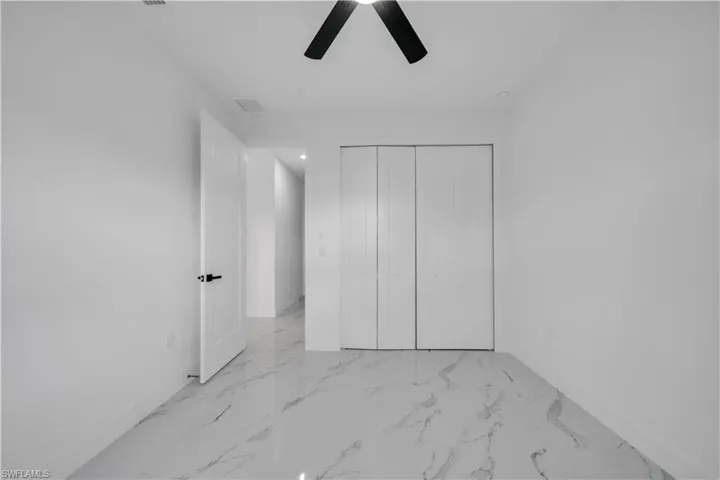 Unfurnished bedroom with a closet, light marble finish flooring, and ceiling fan