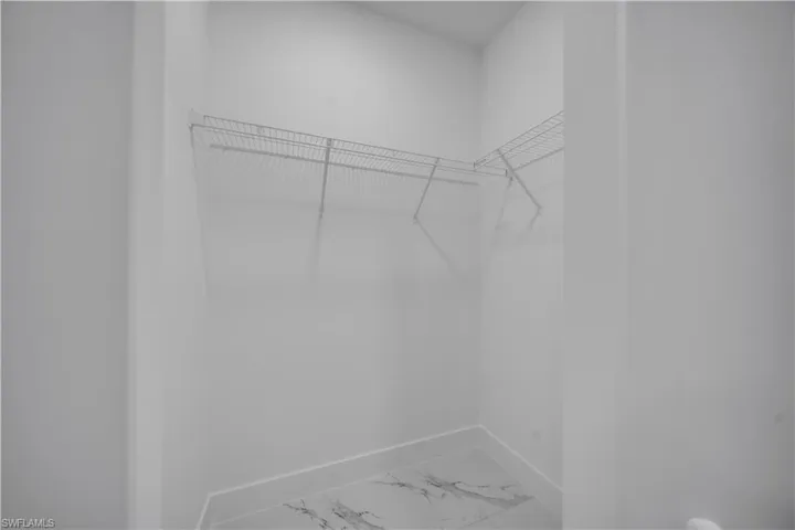 Walk in closet featuring light marble finish flooring