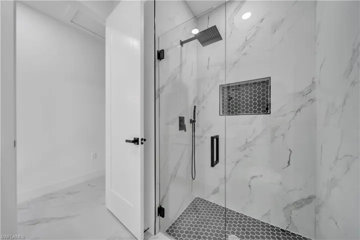 Bathroom with a marble finish shower and light marble finish floors