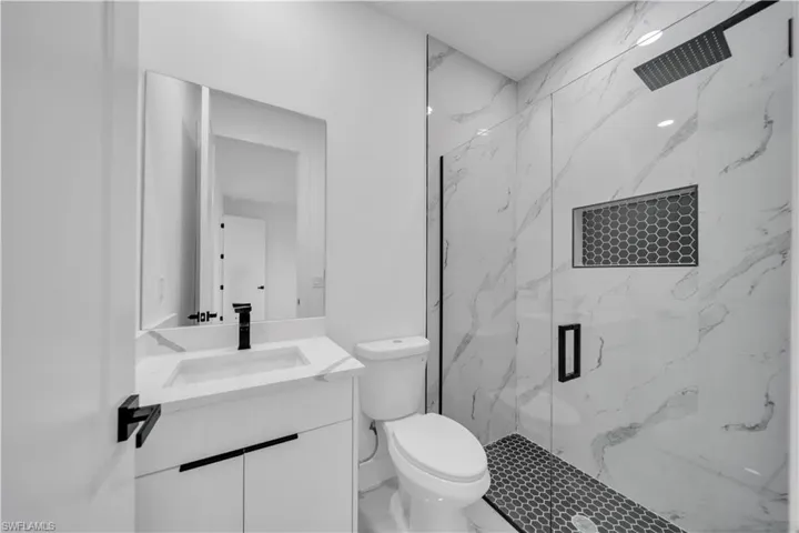 Bathroom with vanity and a marble finish shower