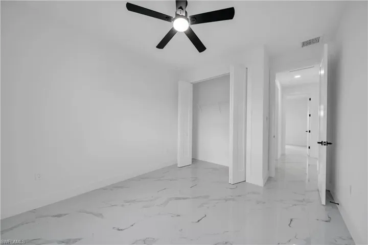 Unfurnished bedroom featuring a closet, ceiling fan, and light marble finish floors