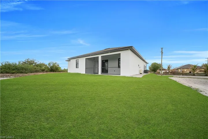 Back of property featuring a yard and stucco siding