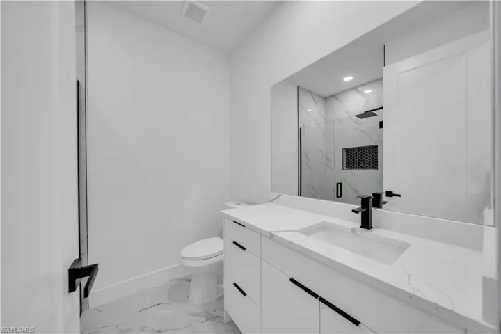 Full bathroom with a marble finish shower, vanity, light marble finish floors, and recessed lighting