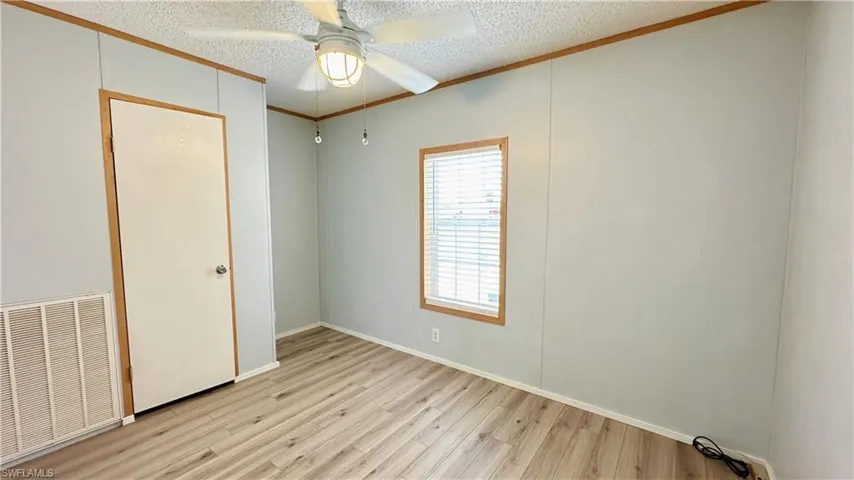 Unfurnished bedroom featuring ceiling fan, light wood-type flooring, and a textured ceiling