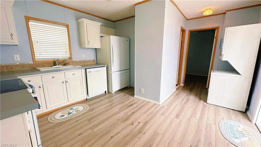 Kitchen featuring sink, light wood-type flooring, white cabinetry, and white appliances