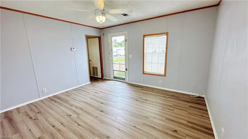 Empty room with ceiling fan, a textured ceiling, and light hardwood / wood-style floors