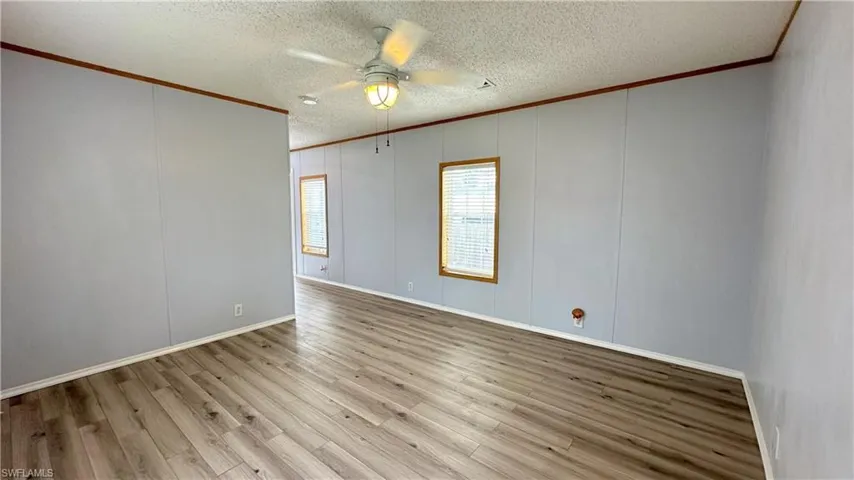 Spare room with ceiling fan, light hardwood / wood-style flooring, a textured ceiling, and ornamental molding