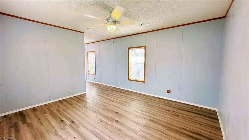 Unfurnished room with ceiling fan, crown molding, light wood-type flooring, and a textured ceiling