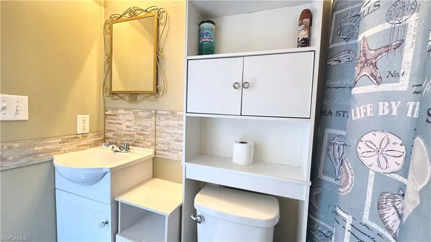 Bathroom featuring decorative backsplash, vanity, and toilet