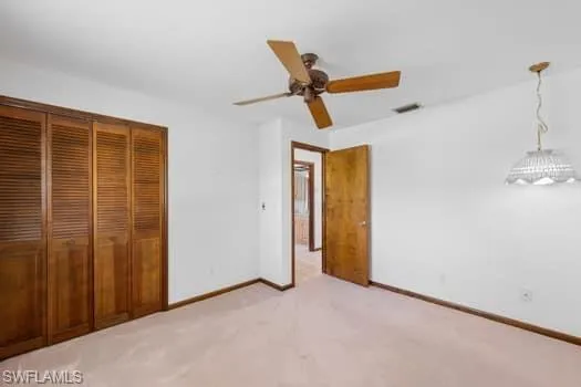 Unfurnished bedroom with light colored carpet, ceiling fan, and a closet