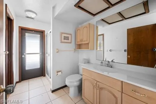 Full bath featuring vanity, light tile patterned flooring, and a stall shower