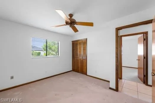 Unfurnished bedroom with light carpet, a closet, and a ceiling fan