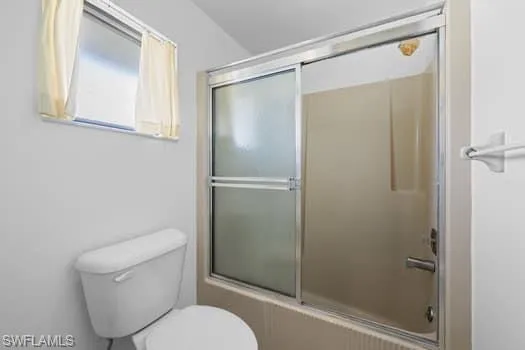 Full bath featuring enclosed tub / shower combo and toilet