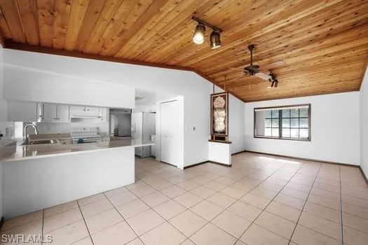 Kitchen featuring open floor plan, lofted ceiling, light countertops, wood ceiling, and white cabinetry