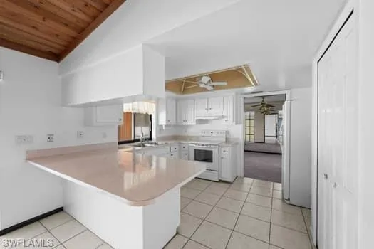 Kitchen featuring white cabinetry, a peninsula, light countertops, white appliances, and light tile patterned flooring