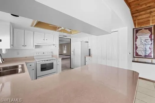Kitchen with white cabinets, white appliances, light countertops, a peninsula, and wooden ceiling