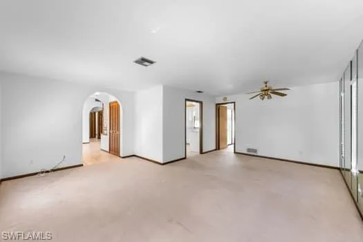 Unfurnished room featuring arched walkways and a ceiling fan