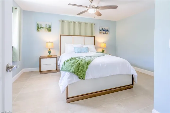 Bedroom featuring tile flooring, light blue walls, and a ceiling fan with integrated lighting