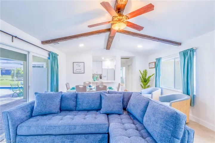 Vaulted ceiling featuring exposed wood beams and a ceiling fan with integrated lighting