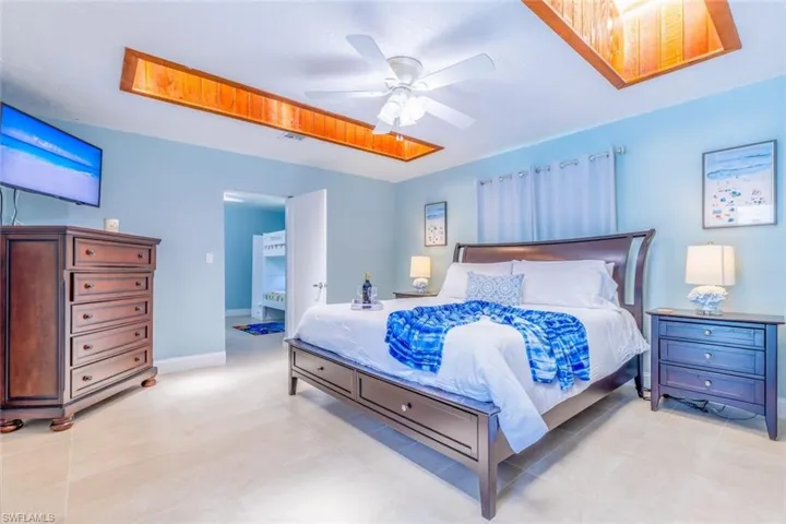 Spacious sleeping area featuring light blue walls, wood-finish ceiling accents, and light-toned tile flooring