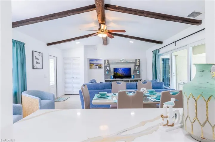 Open-concept living area with vaulted ceilings featuring exposed wood beams