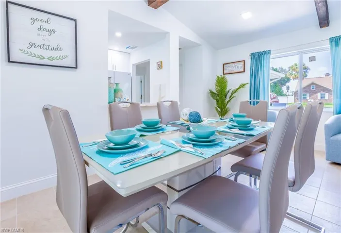 Bright dining area featuring tile flooring and a window with turquoise drapes