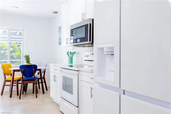 Bright kitchen featuring white cabinetry, a built-in microwave, an electric range, and a panel-ready refrigerator with a water dispenser