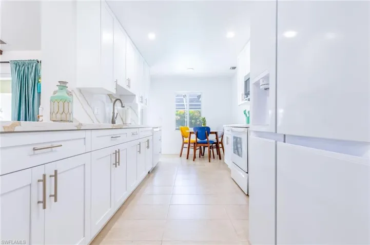Modern kitchen featuring white cabinetry, light-toned tiled flooring, and integrated stainless steel appliances