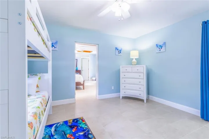 Spacious room featuring light blue walls, tile flooring, white baseboards, and a ceiling fan