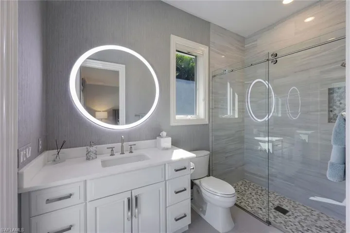 En suite guest bathroom with updated walk-in shower; bathroom accessible to the pool.