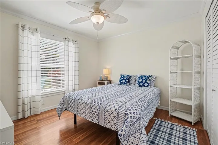 Guest bedroom featuring crown molding, Pergo floors, closet & ceiling fan.