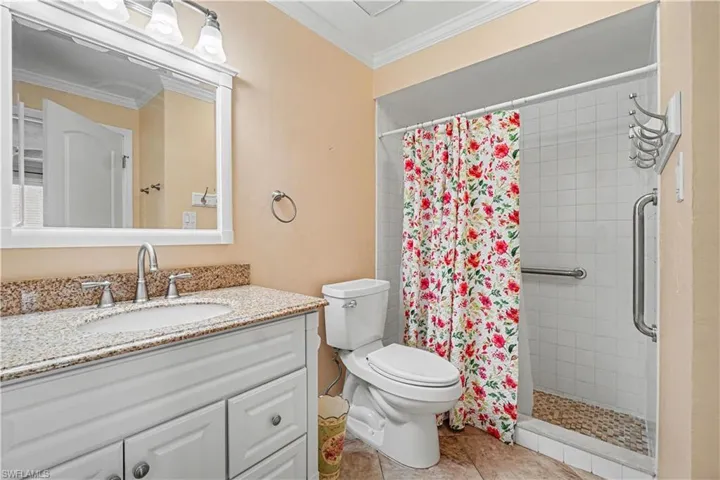 Updated Primary Bath with walk in shower, tiled flooring, crown molding & closet.
