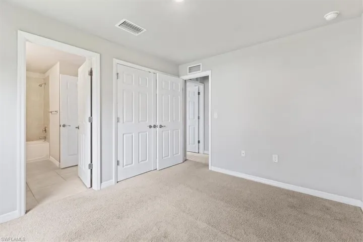 Unfurnished bedroom featuring light colored carpet, a closet, and connected bathroom