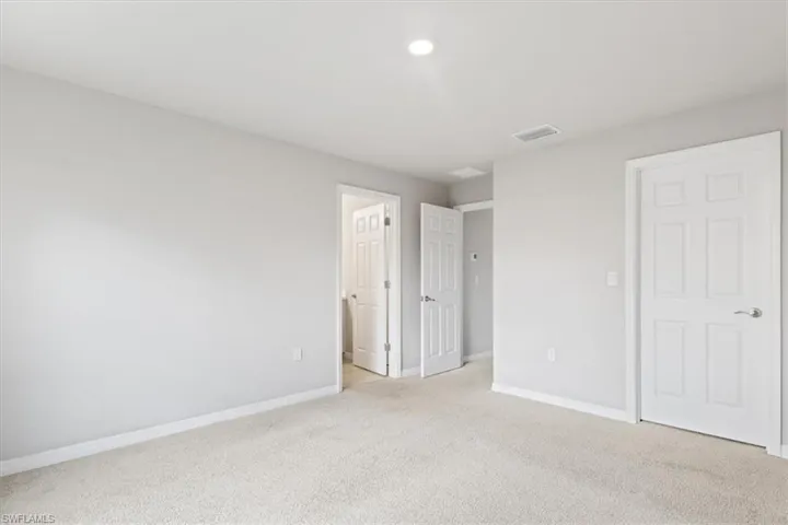 Unfurnished bedroom featuring light colored carpet and baseboards