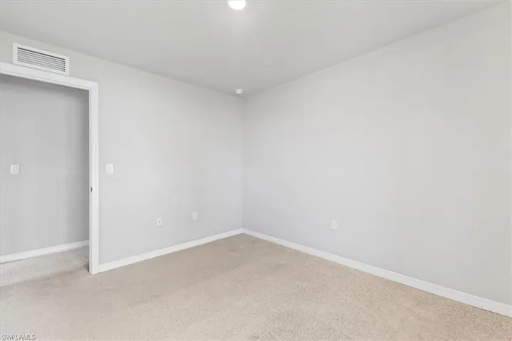Unfurnished room featuring baseboards and light carpet