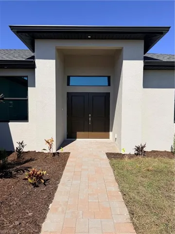 View of exterior entry featuring stucco siding, roof with shingles, and french doors
