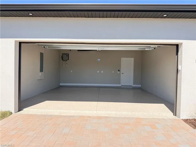 Garage featuring driveway, electric panel, and tankless water heater