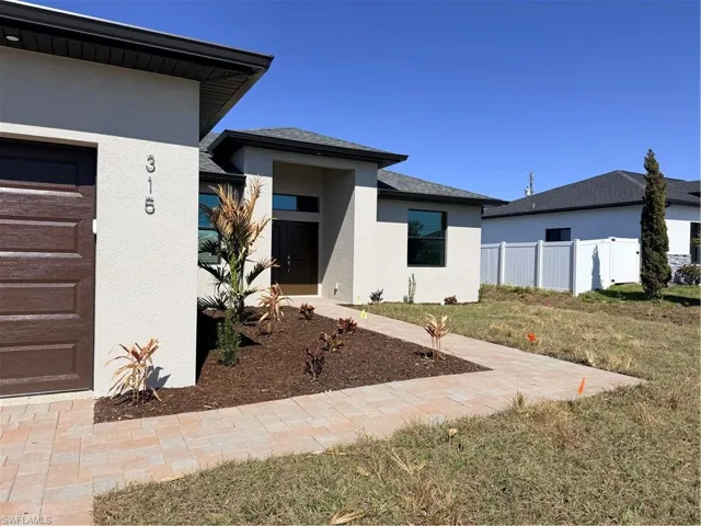 Doorway to property featuring stucco siding and roof with shingles