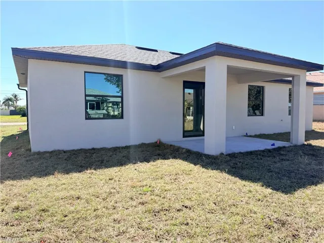 Back of property with a yard, a patio, stucco siding, and roof with shingles