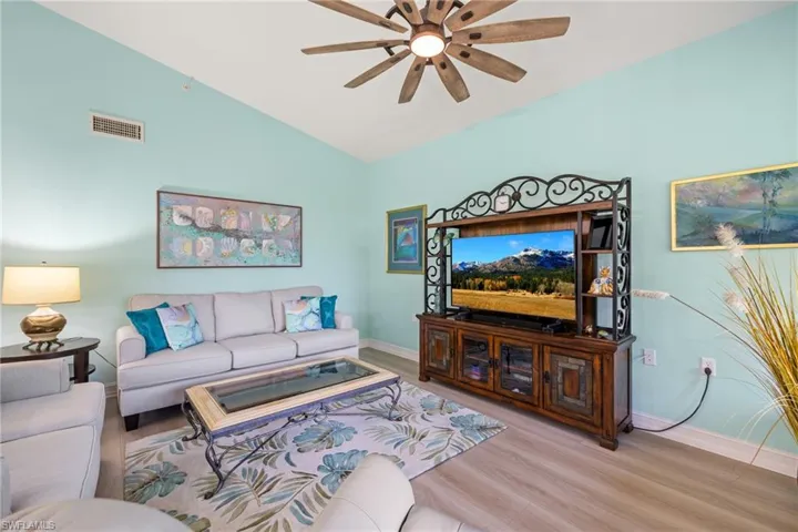Living room with lofted ceiling, ceiling fan, and LV flooring.  Sofa and Loveseat included with sale.
