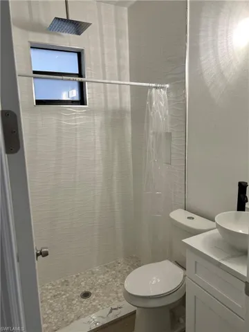 Bathroom with curtained shower, vanity, and toilet