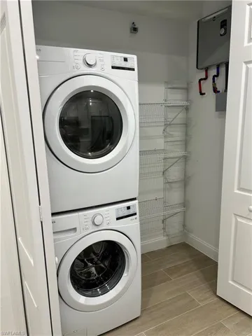 Washroom featuring stacked washing maching and dryer and light hardwood / wood-style flooring