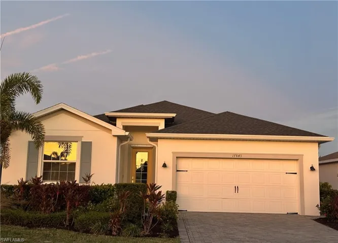 View of front of home with stucco siding, driveway, a garage, and roof with shingles