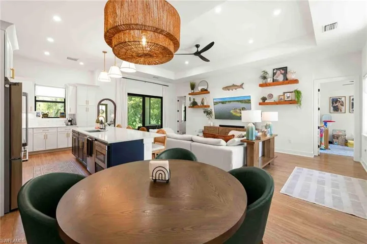 Open-concept living area with wood-finish flooring, a tray ceiling, recessed lighting, and a ceiling fan
