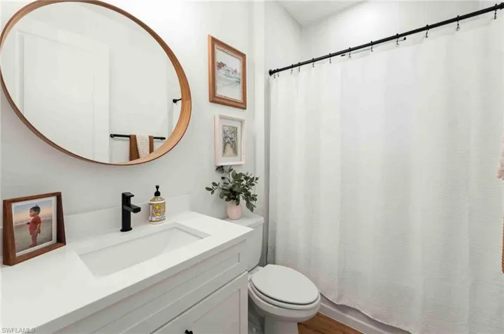 White vanity with integrated sink, matte black faucet, and wood-finish flooring