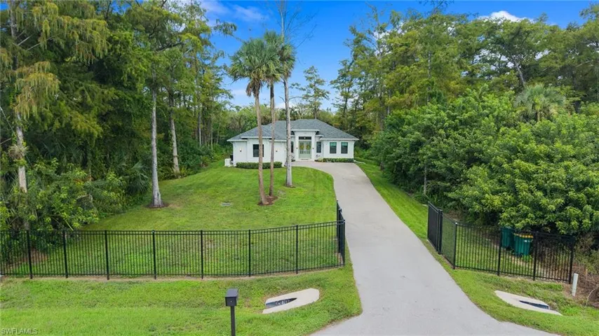 Gated property entrance with a long paved driveway