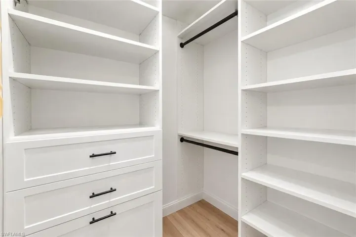 Built-in closet system featuring multiple shelving units, integrated drawers with dark hardware, and hanging rods